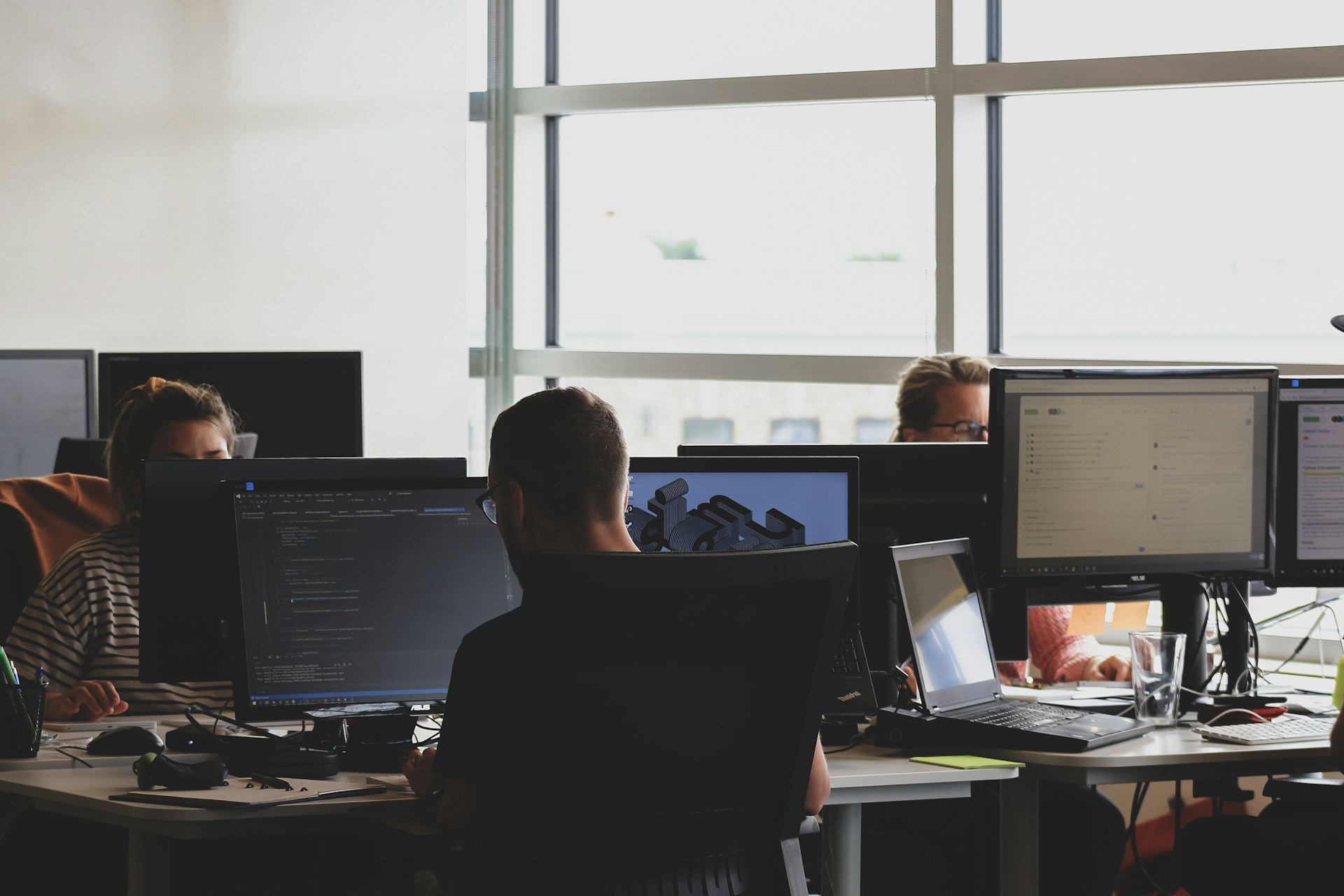 Developers working at desks with multiple monitors