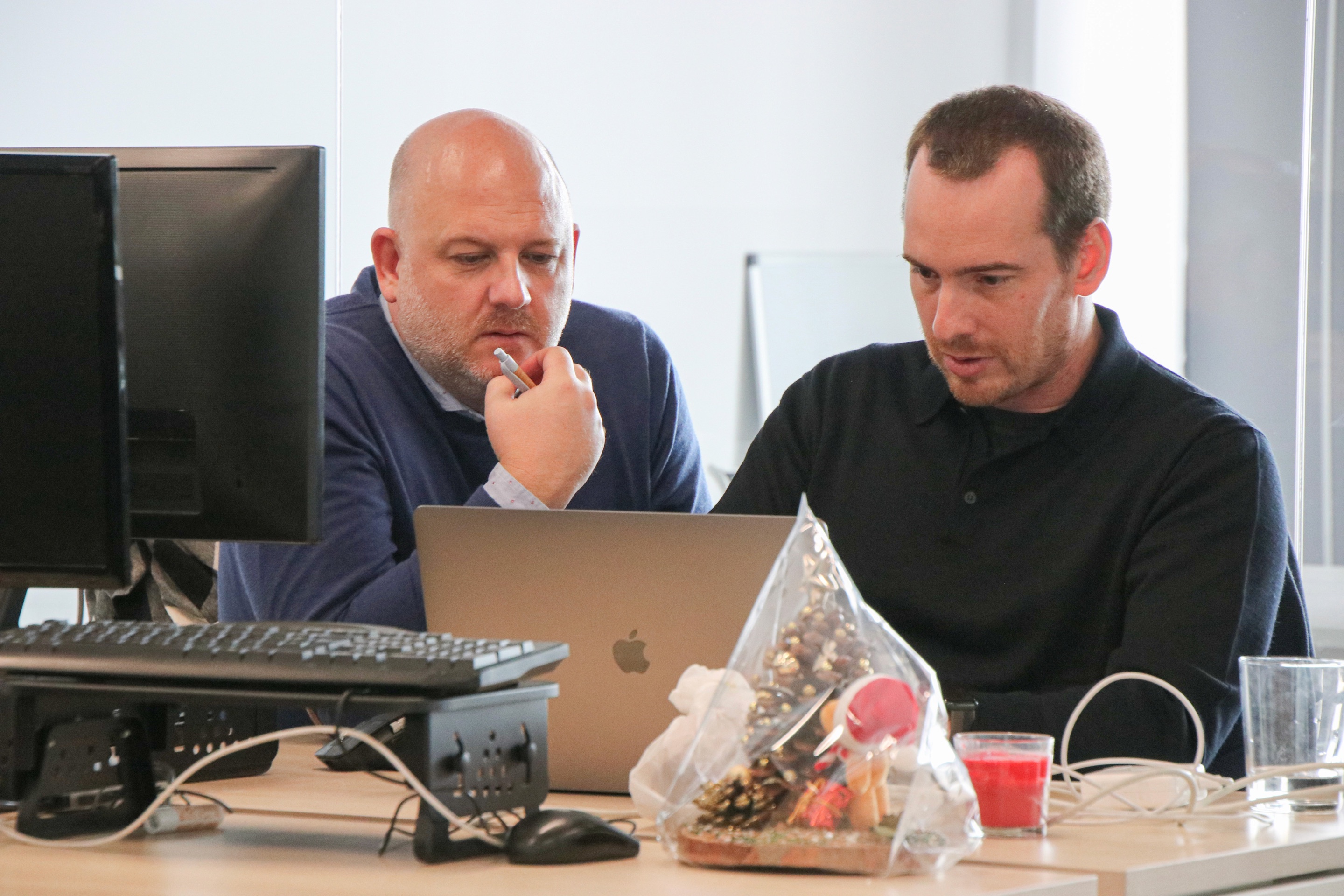 Two colleagues reviewing work on a laptop at a desk