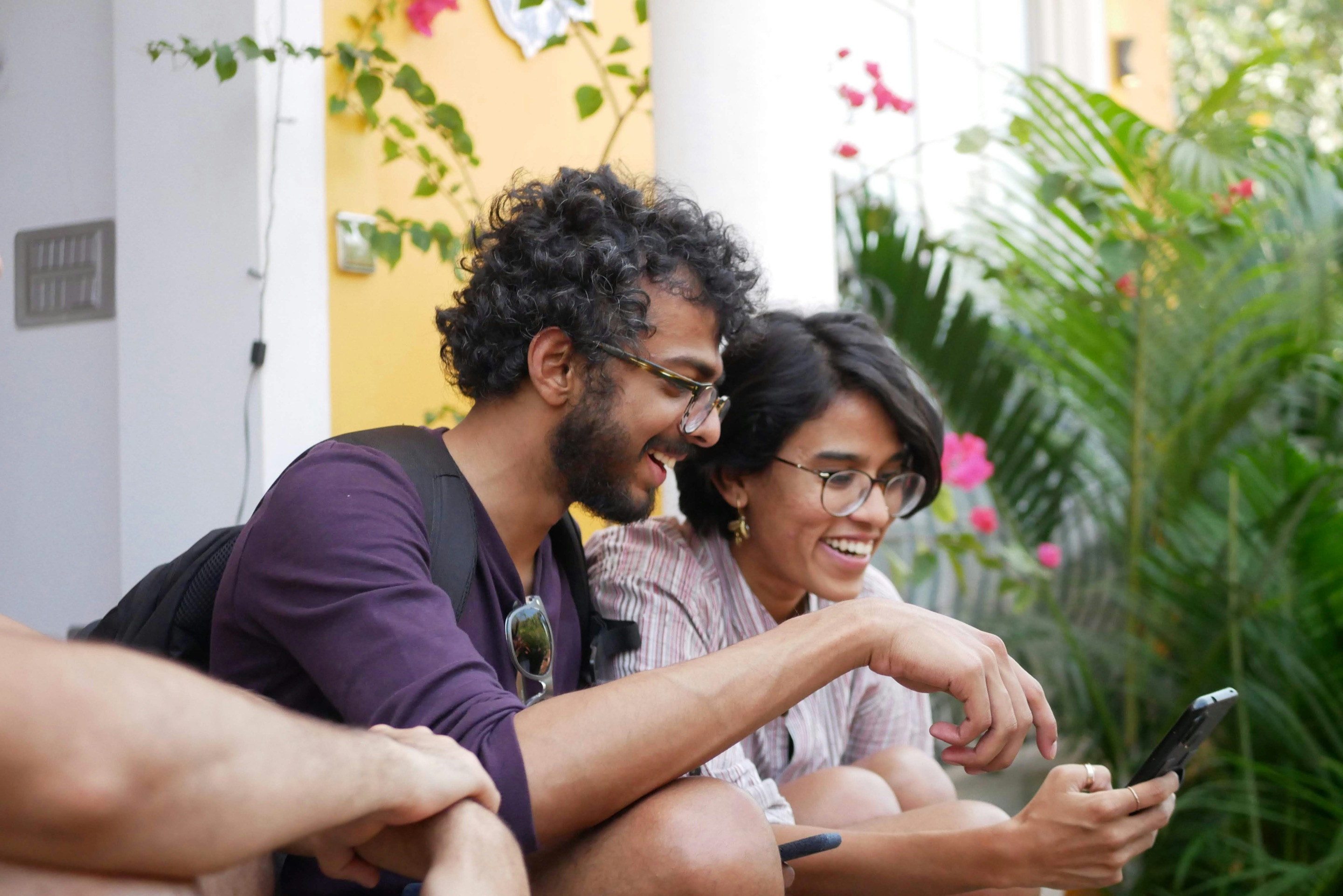 Two people smiling at a smartphone outdoors