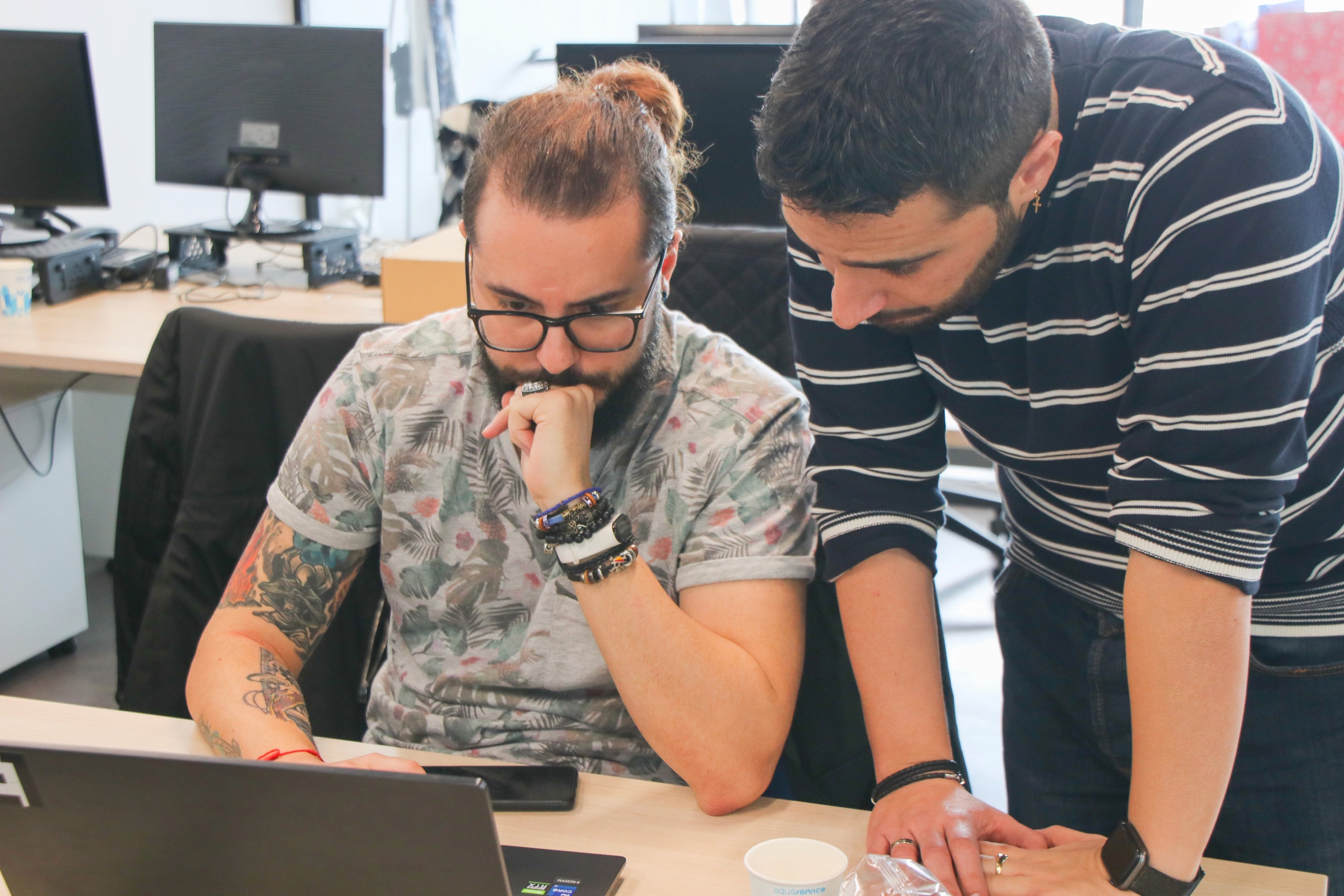 Two developers looking at a laptop together at a desk