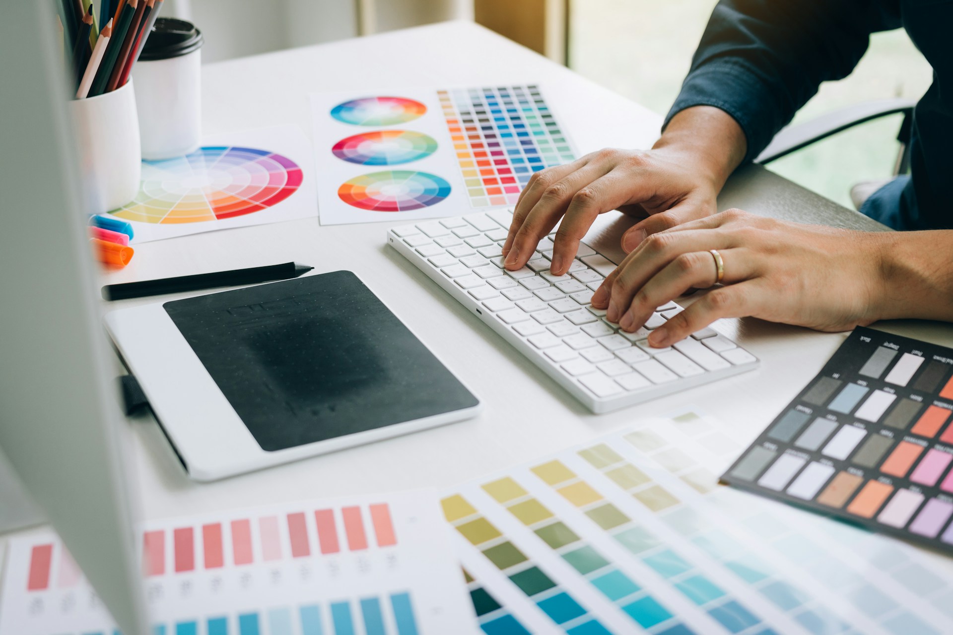 Designer at a keyboard surrounded by colour swatches
