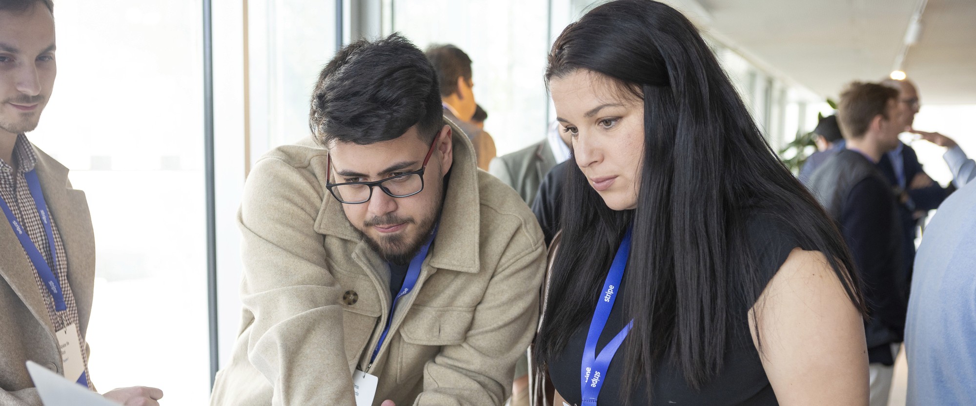 Two people wearing lanyards looking at a screen at an event