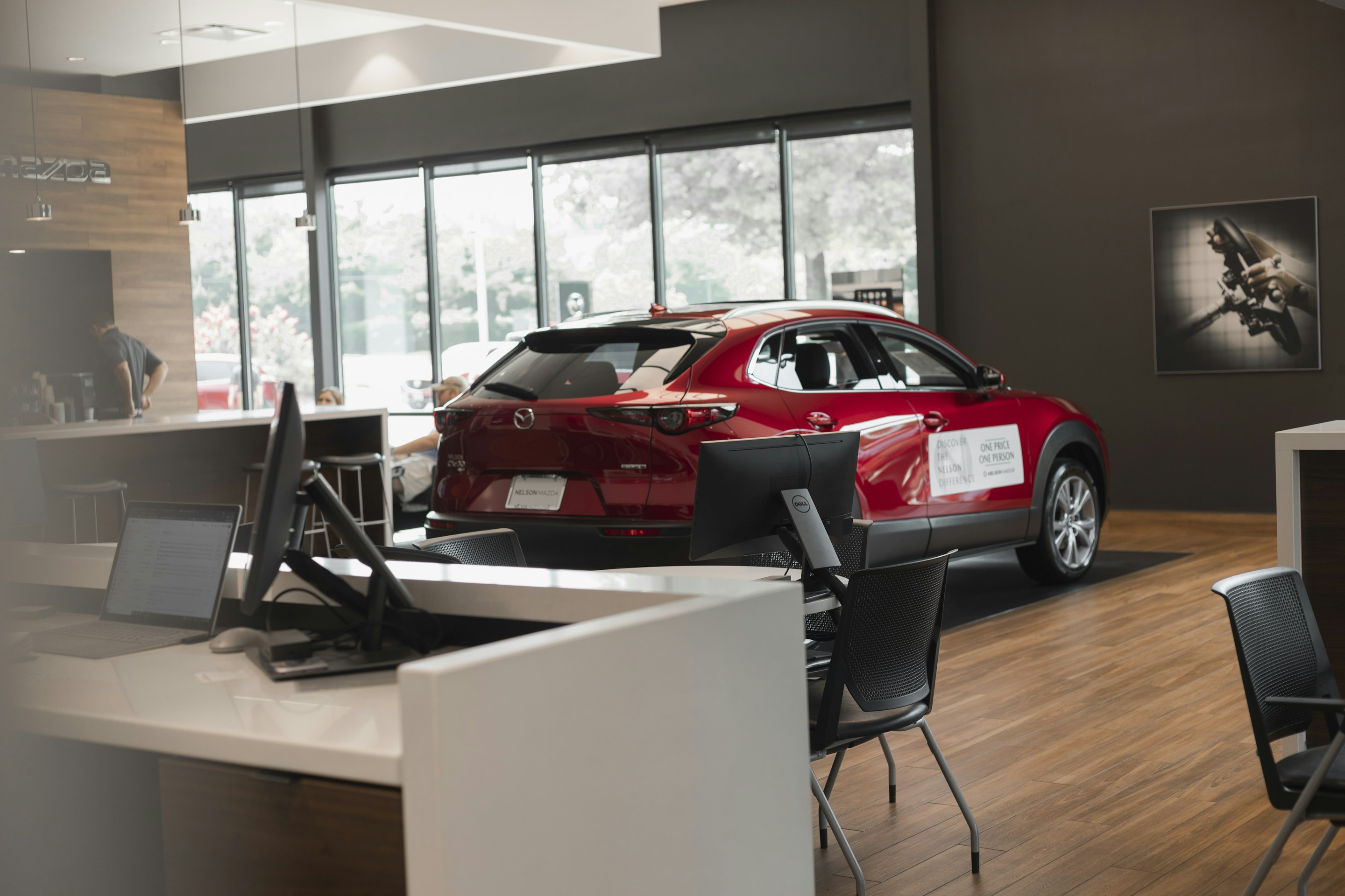 Red SUV on display inside a car showroom beside sales desks