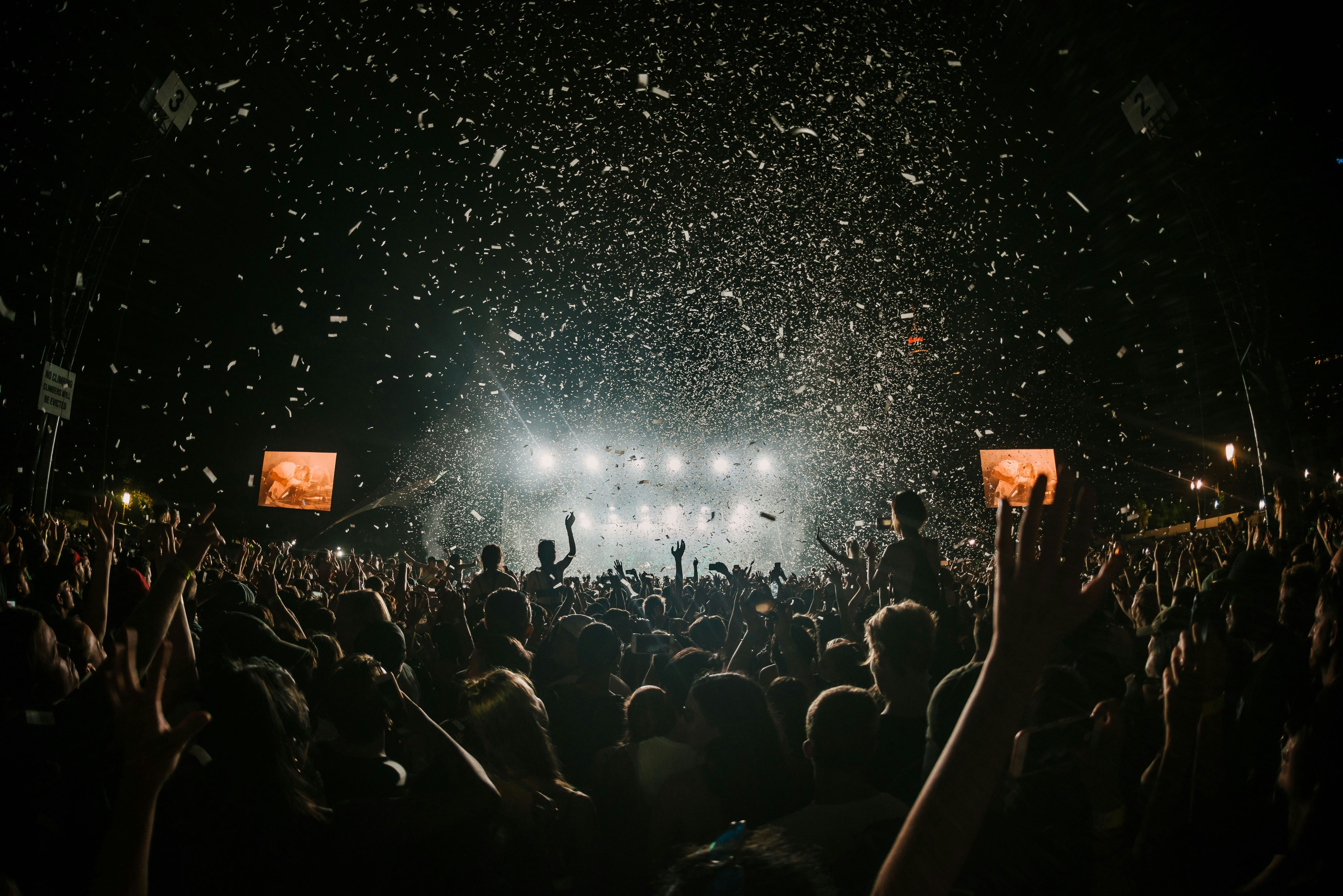 Concert crowd under stage lights with confetti falling