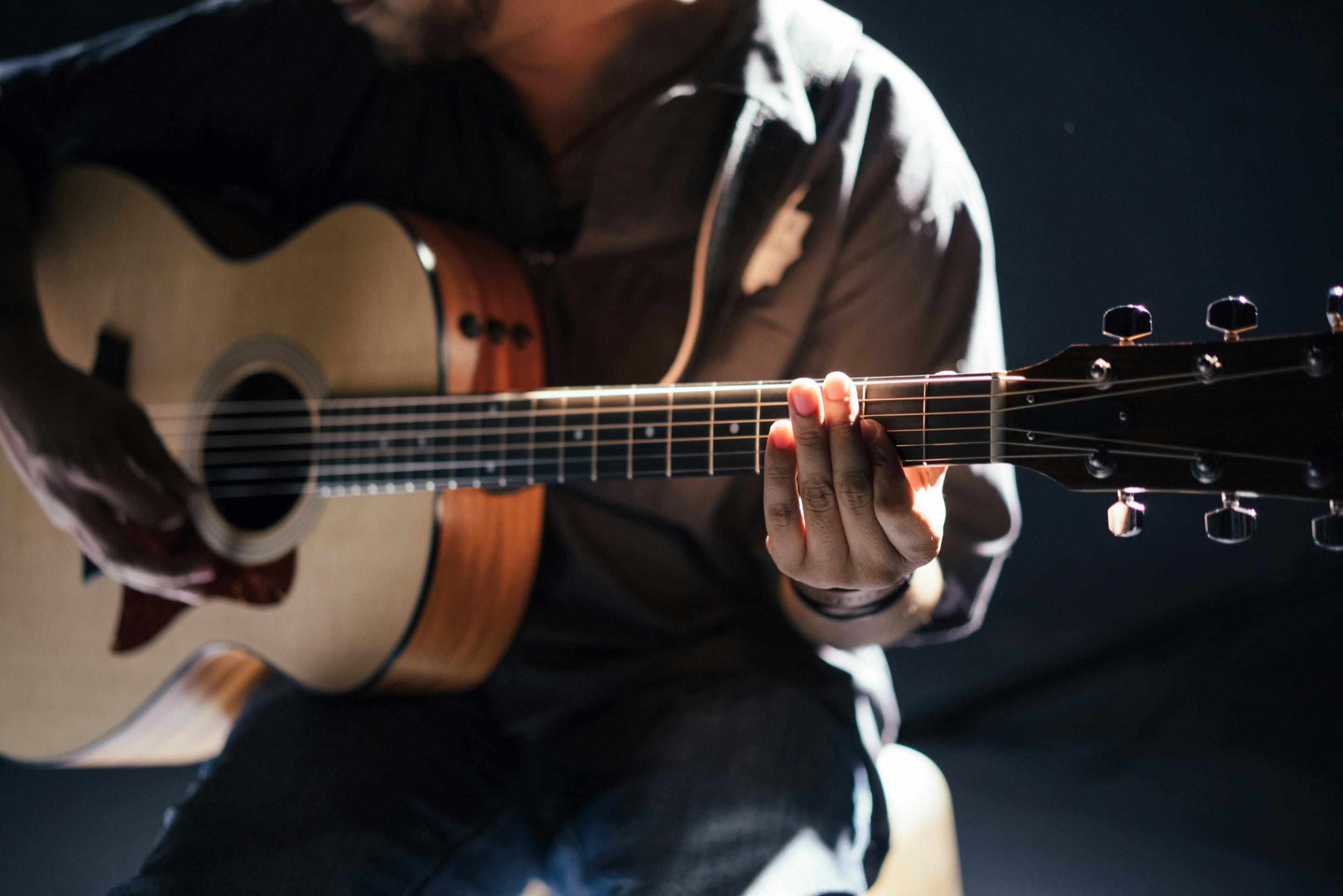 Musician playing an acoustic guitar under a spotlight