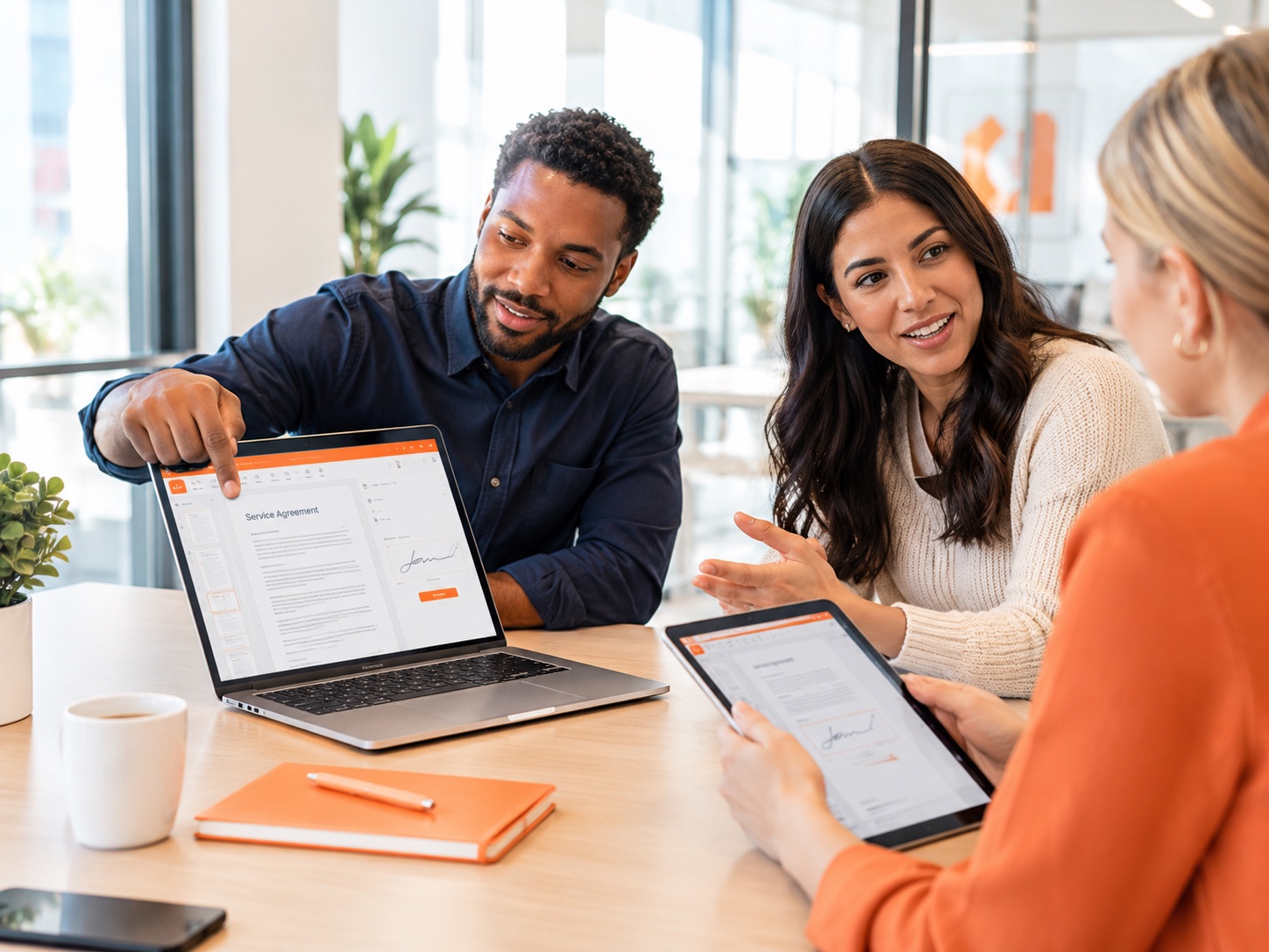 Three colleagues reviewing a service agreement on a laptop and a tablet
