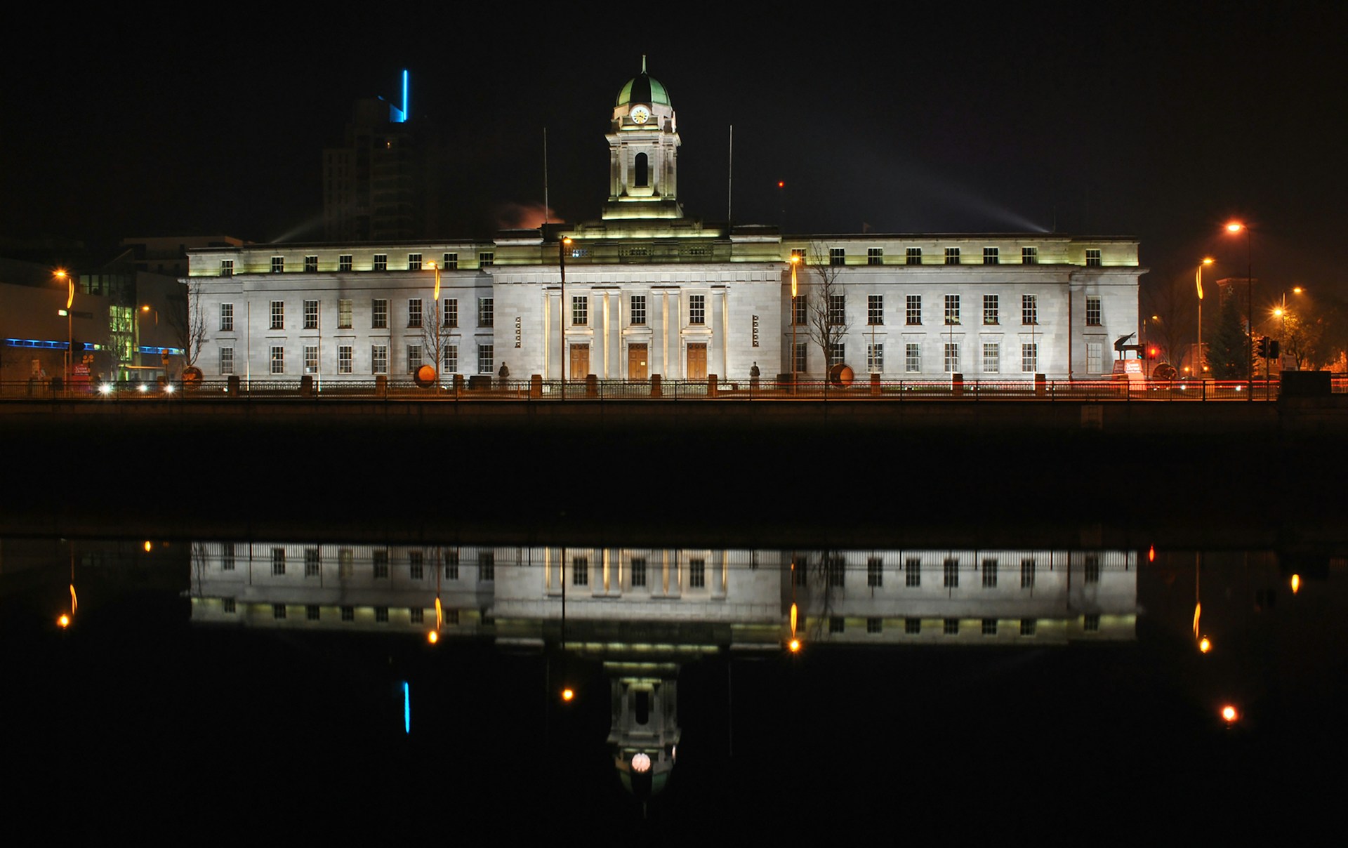 Floodlit civic building reflected in a river at night