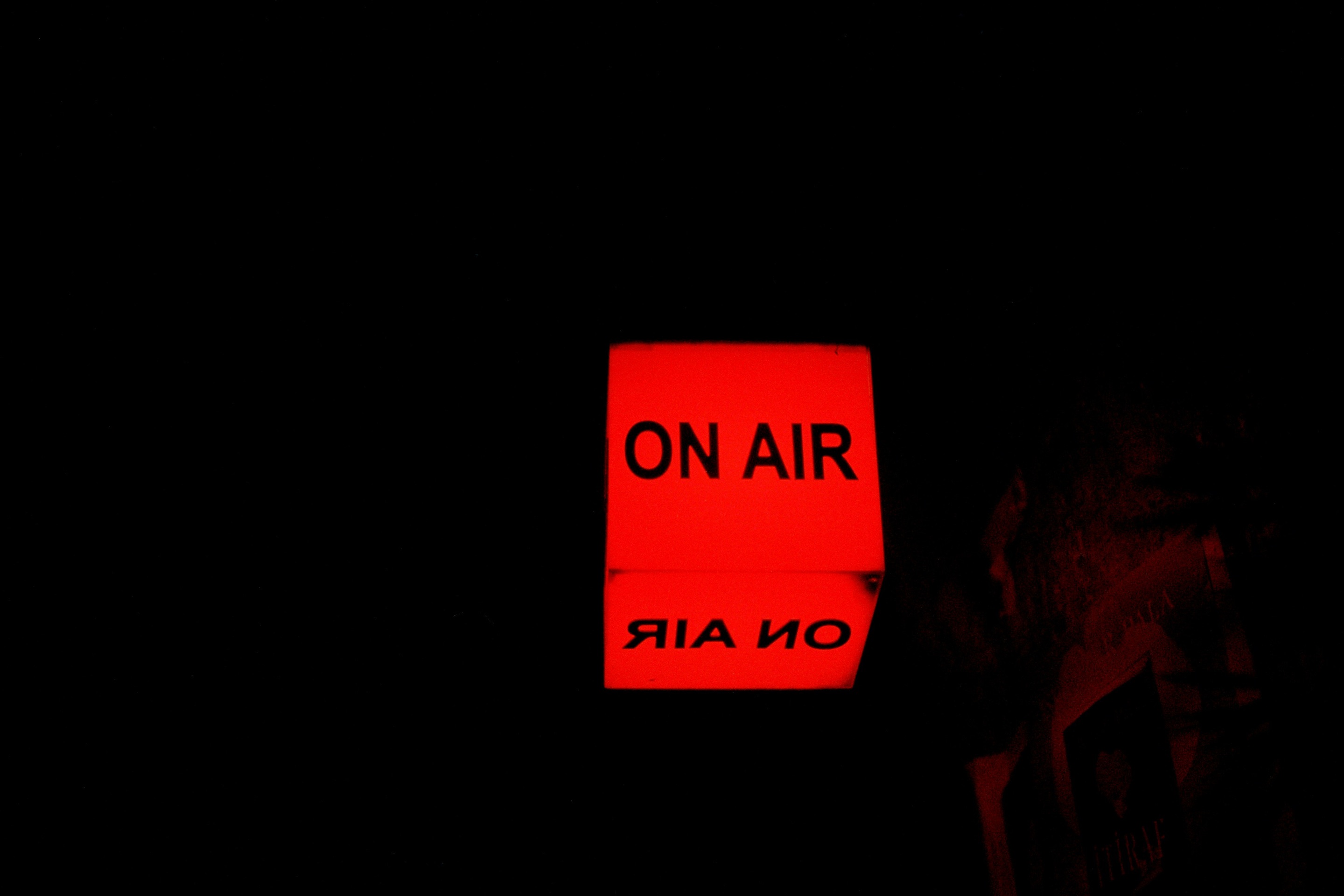 Red illuminated On Air sign in a dark room