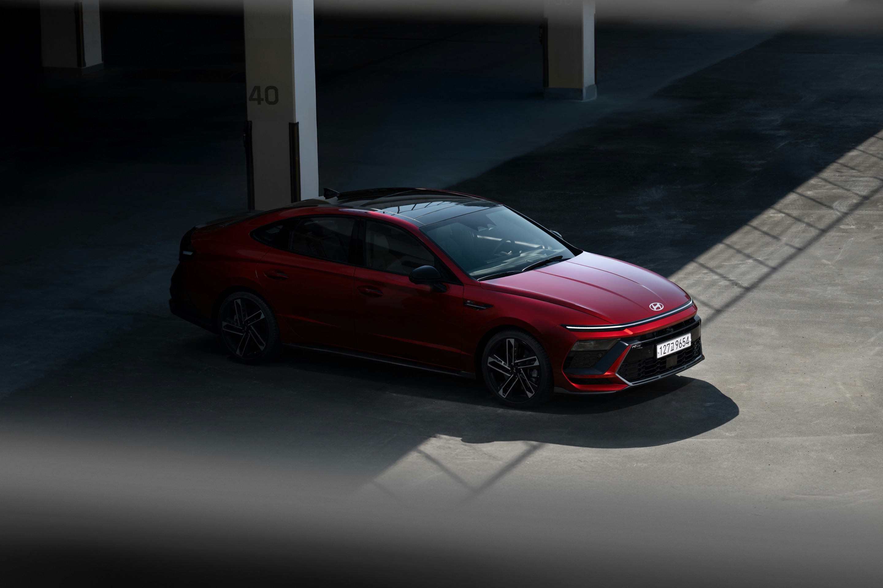 Red saloon car parked in a shadowy car park