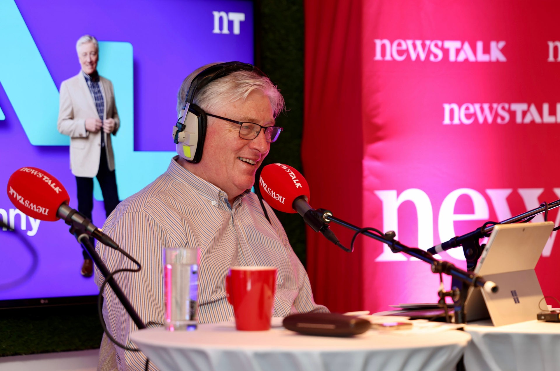 Newstalk presenter speaking into a branded microphone